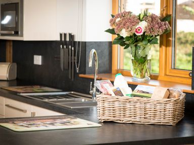 A kitchen countertop with a basket of groceries and flowers in a vase by the window at Atlas in Cawdor near Inverness