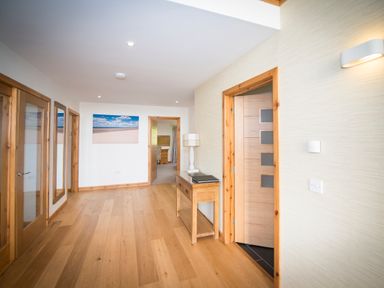 A hallway with wooden floors doors and a table with a lamp at Atlas in Cawdor near Inverness