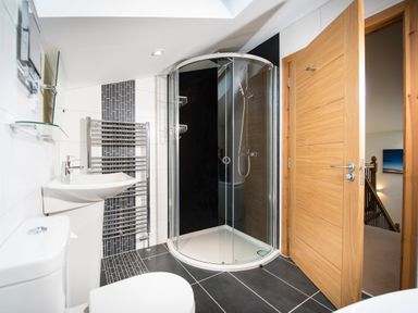A bathroom with a toilet sink glass shower and a wooden door at Atlas in Cawdor near Inverness