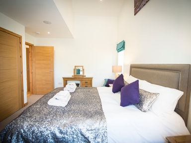 A bedroom with a bed with purple pillows and a silver blanket at Atlas in Cawdor near Inverness