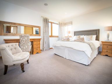 A bedroom with a bed side tables lamps a dressing table and chairs at Atlas in Cawdor near Inverness