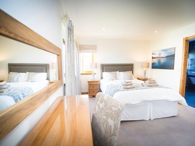 A bedroom with a bed towels on bed bedside tables with lamps a large mirror and a chair at Atlas in Cawdor near Inverness