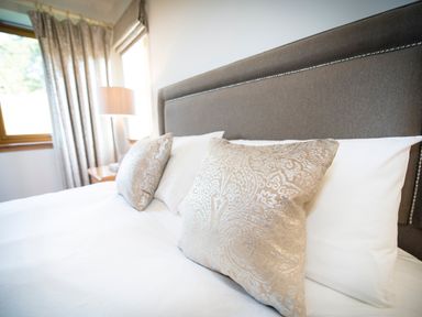 A bed with patterned cushions and white pillows near a lamp and window in a bedroom at Atlas in Cawdor near Inverness