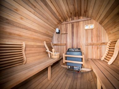 An interior of a wooden sauna with benches on both sides a heater and a wooden bucket with ladle at Atlas in Cawdor near Inverness