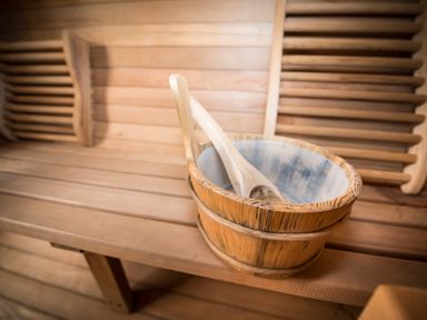 A wooden bucket with a wooden ladle on a wooden bench inside a sauna at Atlas in Cawdor near Inverness