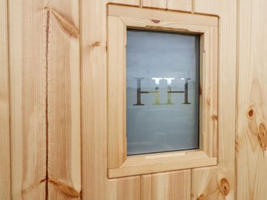A wooden door with a small frosted glass window with the letters HH at Shepherds Hut in Garthorpe near Scunthorpe