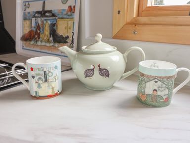 A kitchen counter with a teapot and two mugs near a wooden window at Shepherds Hut in Garthorpe near Scunthorpe
