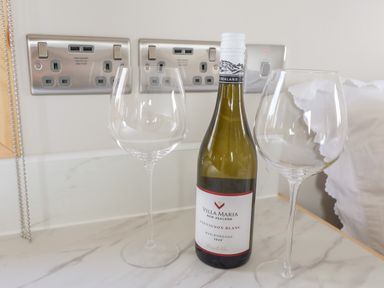 A bottle of Villa Maria Sauvignon Blanc with two empty wine glasses on a countertop at Shepherds Hut in Garthorpe near Scunthorpe