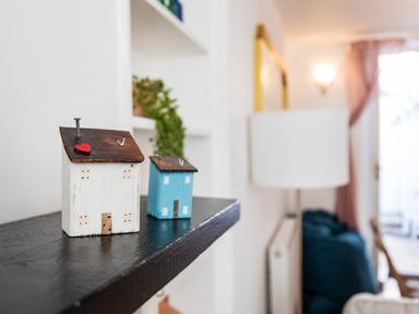 Two small decorative wooden houses on a black shelf in a living room at 11 Belgravia Street in Penzance