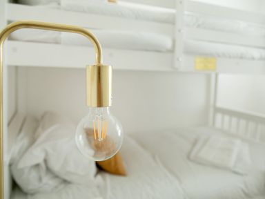 A bunk bed with white bedding and a brass lamp with a clear light bulb at 11 Belgravia Street in Penzance