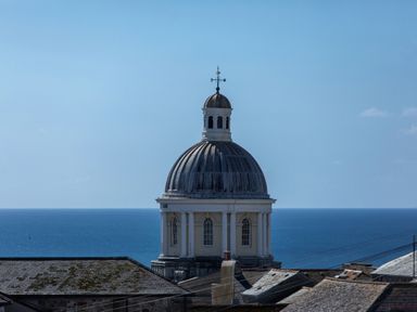 A dome building with a weather vane overlooking the ocean and rooftops at 11 Belgravia Street in Penzance
