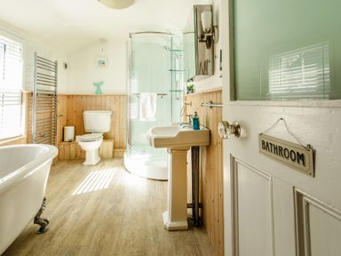 A bathroom with a clawfoot tub toilet pedestal sink shower and wood paneling at 11 Belgravia Street in Penzance