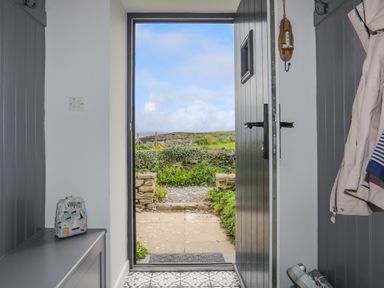 A doorway view from inside showing an open black door leading to a garden path at Bwthyn Y Swnt in Moelfre
