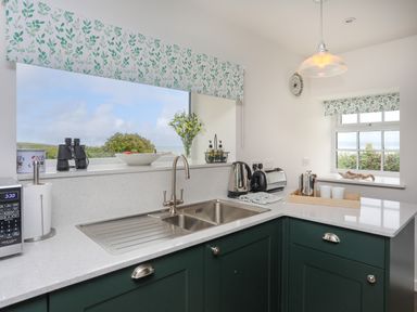 A kitchen with a double sink kettle toaster and microwave at Bwthyn Y Swnt in Moelfre