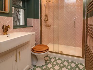 A bathroom with a sink cabinet toilet with wooden seat shower enclosure and patterned floor tiles at Secret Garden 34C Clarence Street Dartmouth