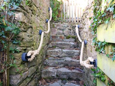 Stone steps between stone walls with rope handrails and some ivy growing at Secret Garden 34C Clarence Street Dartmouth
