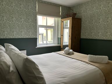 A bedroom with a bed, rolled towels, a window with a blind, and a wardrobe with a mirror at Secret Garden 34C Clarence Street Dartmouth
