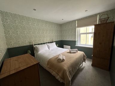 A bedroom with a double bed and wooden cabinets at Secret Garden 34C Clarence Street Dartmouth