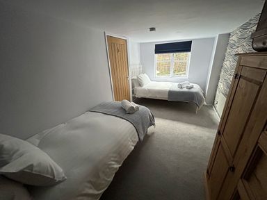 A bedroom with two single beds a wooden wardrobe and a window at Secret Garden 34C Clarence Street Dartmouth