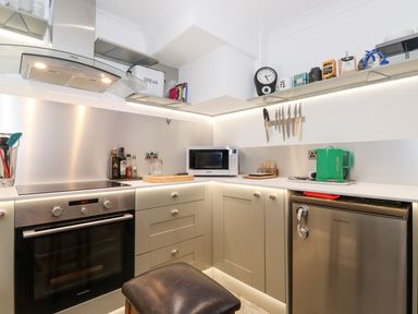 A kitchen corner with a stove oven microwave knives on a magnetic strip and a kettle at Cherry Tree Cottage in Windermere