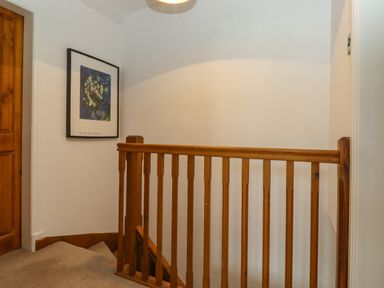 Wooden banister at the top of a carpeted staircase with a framed artwork on the wall