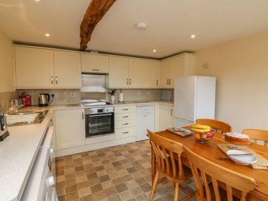 A kitchen with beige cabinets a wooden dining table with chairs and food items on it at Hunstone Barn in South Molton