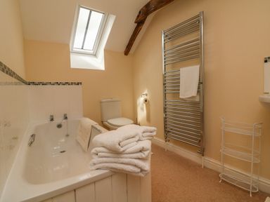 A bathroom with a bathtub toilet towel rack towels and a skylight window at Hunstone Barn in South Molton