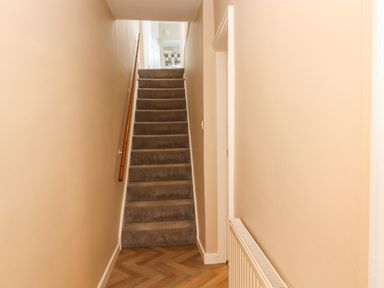 A hallway with wooden flooring carpeted stairs and a radiator at Bay Tree Cottage in Keswick