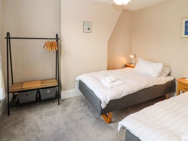 A bedroom with two single beds a clothes rack with hangers and two bedside tables at Bay Tree Cottage in Keswick