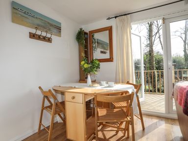 A dining area with a wooden table and chairs next to glass doors leading to a balcony at Treetops in Caernarfon