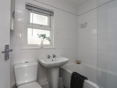 A bathroom with a toilet sink bathtub towel and a window with a vase at Treetops Caernarfon