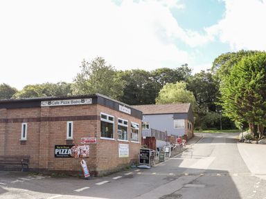 A brick building with signs for a cafe pizza bistro and outdoor seating at Treetops in Caernarfon