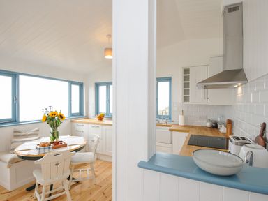 A kitchen and dining area with white cabinetry wooden countertops and blue window frames at Solana Whitsand Bay