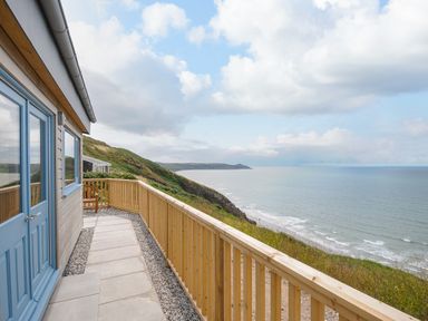 A balcony with wooden railing overlooking a coastal cliff and the sea at Solana Whitsand Bay