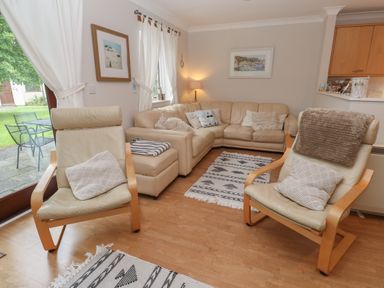 A living room with beige leather chairs a beige sectional sofa and patterned rugs at Alberts Den in Falmouth