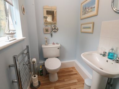 A bathroom with a toilet a sink and wall decorations at Alberts Den in Falmouth