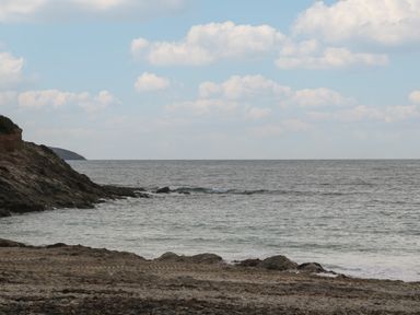 A rocky beach with sea waves and a partly cloudy sky