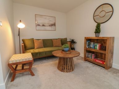 A living room with a green sofa wooden coffee table and bookshelf at Reubens Cottage in Fremington Devon