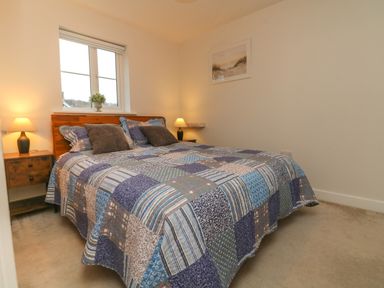 A bedroom with a double bed and two bedside tables with lamps at Reubens Cottage in Fremington Devon