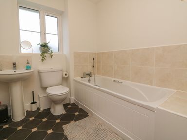 A bathroom with a bathtub a toilet and a sink next to a window at Reubens Cottage in Fremington Devon