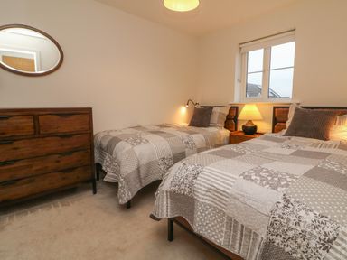 A bedroom with two single beds a wooden dresser and a window at Reubens Cottage Fremington Devon