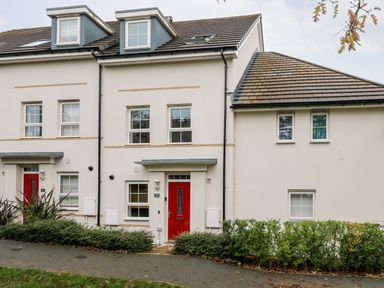 A row of white houses with red front doors and multiple windows at 20 Bishops Way in Falmouth