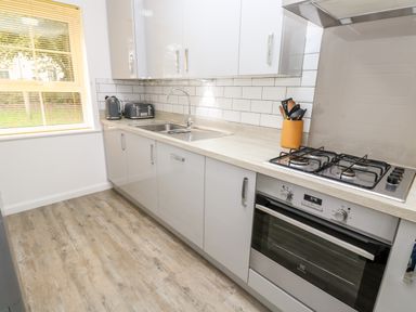 A kitchen with a sink, gas stove, oven, utensils, toaster and kettle next to a window at 20 Bishops Way in Falmouth