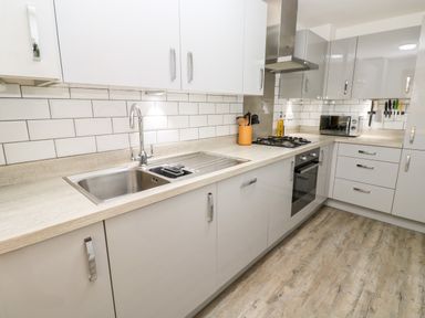A kitchen with white cabinets a sink gas stove oven microwave and knives on a magnetic strip at 20 Bishops Way in Falmouth