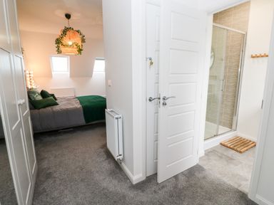A bedroom with a bed and green bedding visible through a doorway next to a bathroom with a glass shower enclosure at 20 Bishops Way in Falmouth
