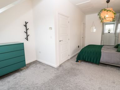 A bedroom with a green chest of drawers a bed with green bedding and a hanging lamp at 20 Bishops Way in Falmouth