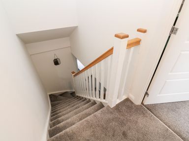 A carpeted staircase with white and wooden railing next to a partially open door at 20 Bishops Way in Falmouth