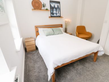 A bedroom with a wooden bed and white bedding with two green pillows at 20 Bishops Way in Falmouth