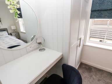 A bedroom corner with a white dressing table mirror and a black chair at 20 Bishops Way in Falmouth