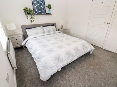 A bedroom with a double bed two bedside tables with lamps a shelf with plants and artwork at 20 Bishops Way Falmouth